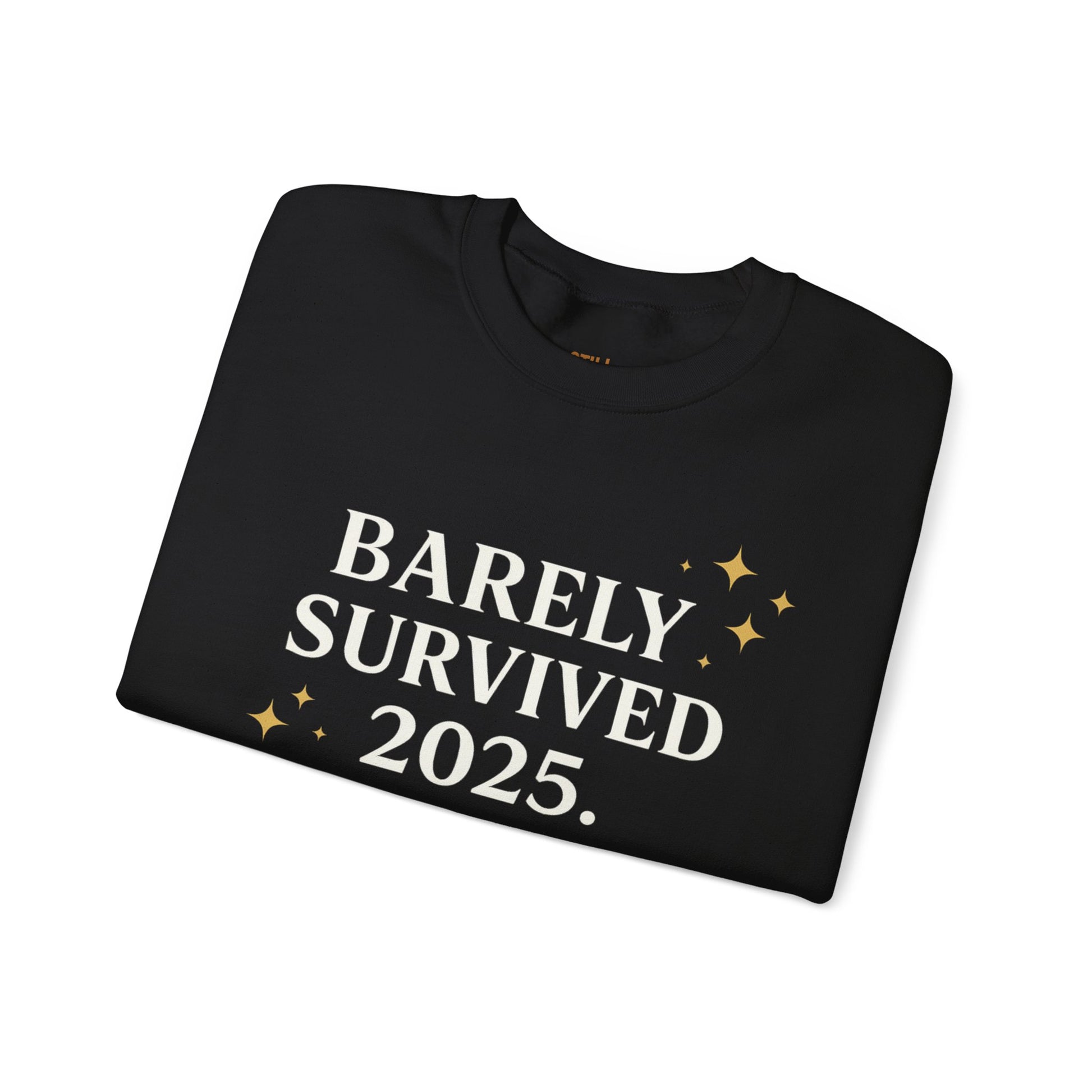 Black crewneck sweatshirt with white and gold text that reads “Barely Survived 2025. Mentally in 2026. Still Adulting: Holiday Edition.”